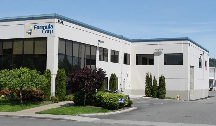Exterior view of the Formula Corp corporate office building with landscaped greenery and large windows.